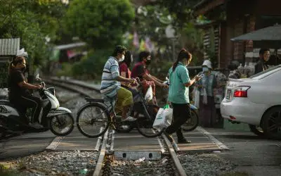 Commuters cross train tracks on foot, bicycle, automobile