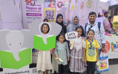 Four Children and their parents stand in front of Let's Read Booth.