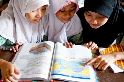 Books for Asia- Textbook Students at a community learning center in Jakarta pore over a brand-new textbook provided by Books for Asia