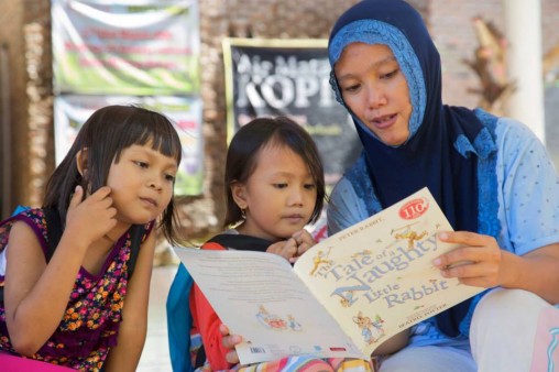 A mother reads The Tale of a Naughty Little Rabbit with her children. Photo by Ed Wray.