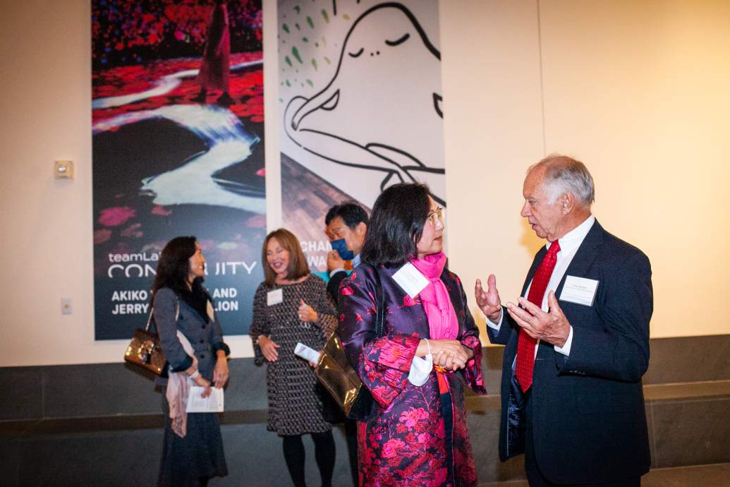 Several people converse in front of artwork