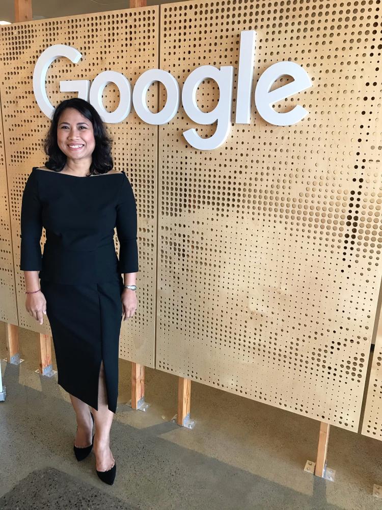 Development Fellow, Apsari Dewi smiles in front of Google sign
