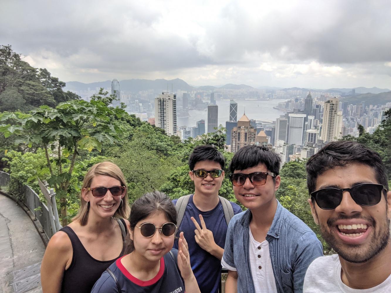 A group takes a selfie in front of the Hong Kong skyline