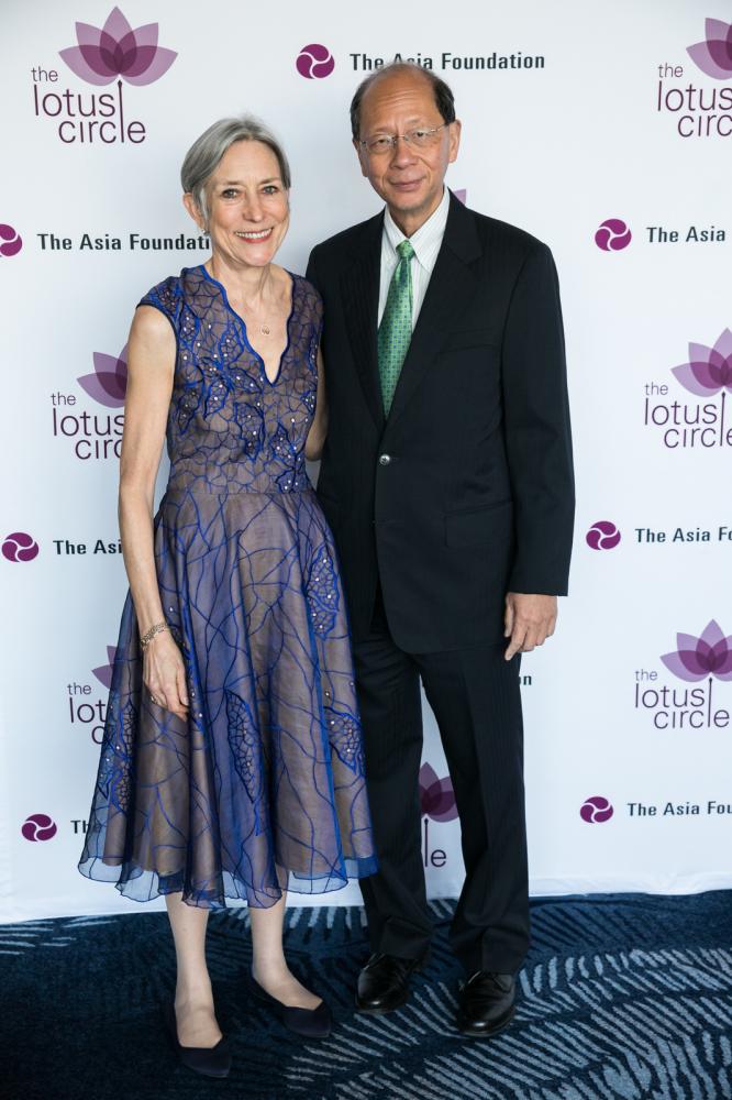 Woman wearing grey/blue gown and man in a black suit with a green tie