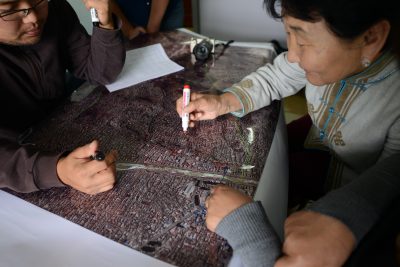 Woman uses a marker to draw on aerial map