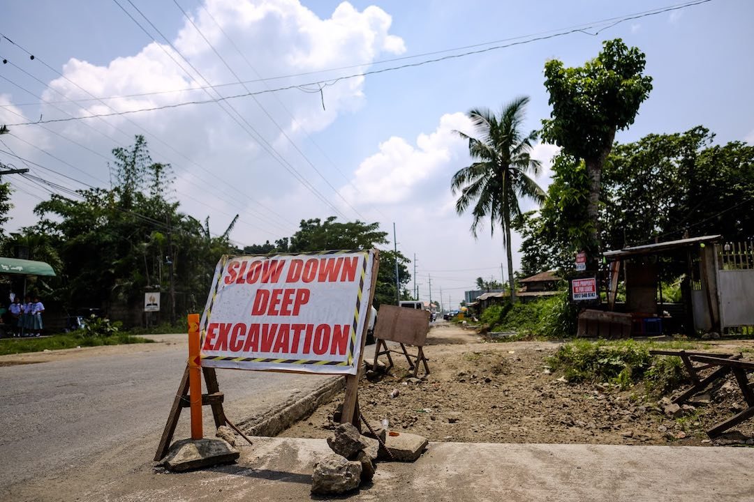 Roadwork in the Philippines, with a sign reading "Slow down deep excavation"