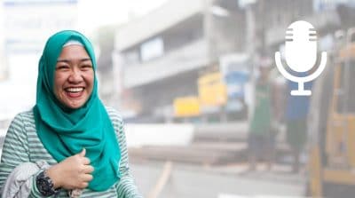Woman in headscarf laughing in front of street construction