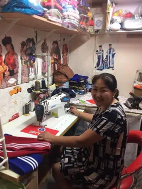 Tsetsegmaa Dorjbat smiling alongside her new sewing equipment