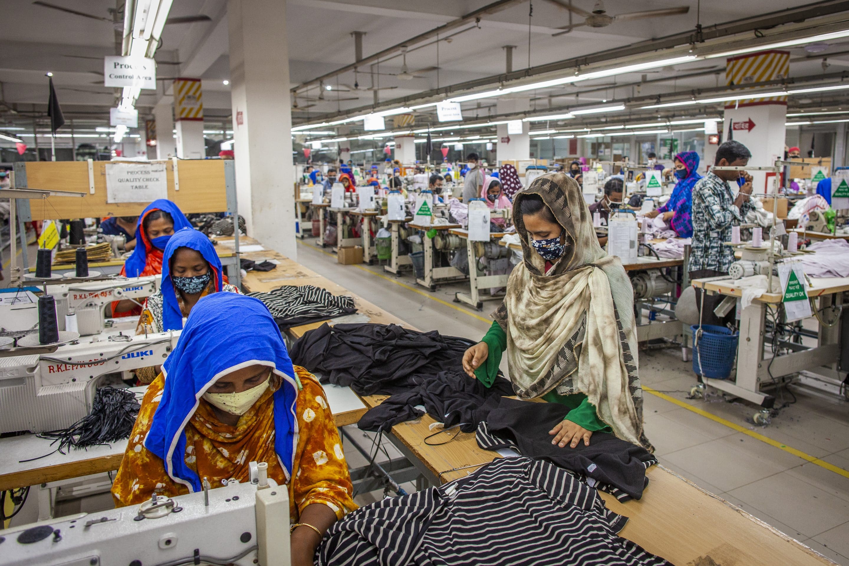 Women work at sewing machines and assemble clothing pieces