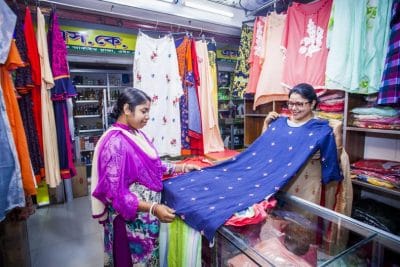 A clothing store owner shows a customer a dress