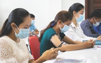 Women, wearing masks, work on training activities on phones