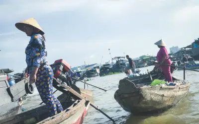 Woman wearing farmers hat stands in boat