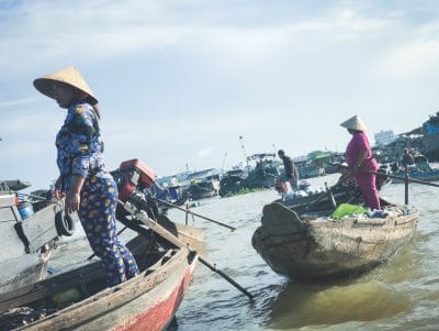 Woman wearing farmers hat stands in boat