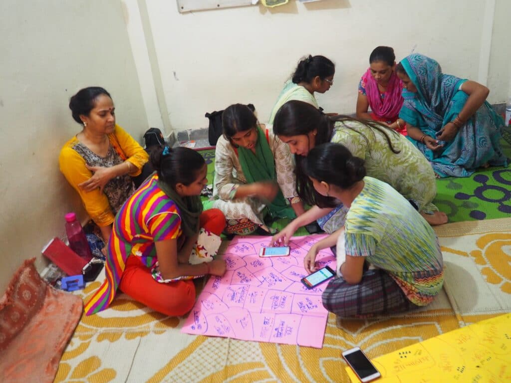 A women-led workshop look over a map and the Safetipin app on their phones.