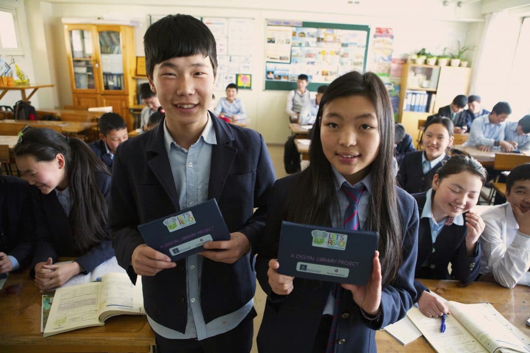 girl and boy hold tablets in a classroom