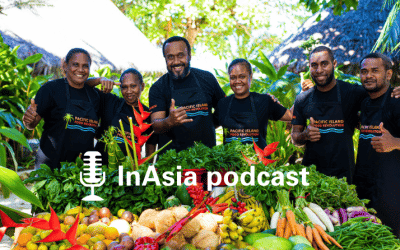 Five participants of the Pacific Island Food Revolution stand behind a cornucopia of Pacific Island vegetables and grains. InAsia podcast logo.