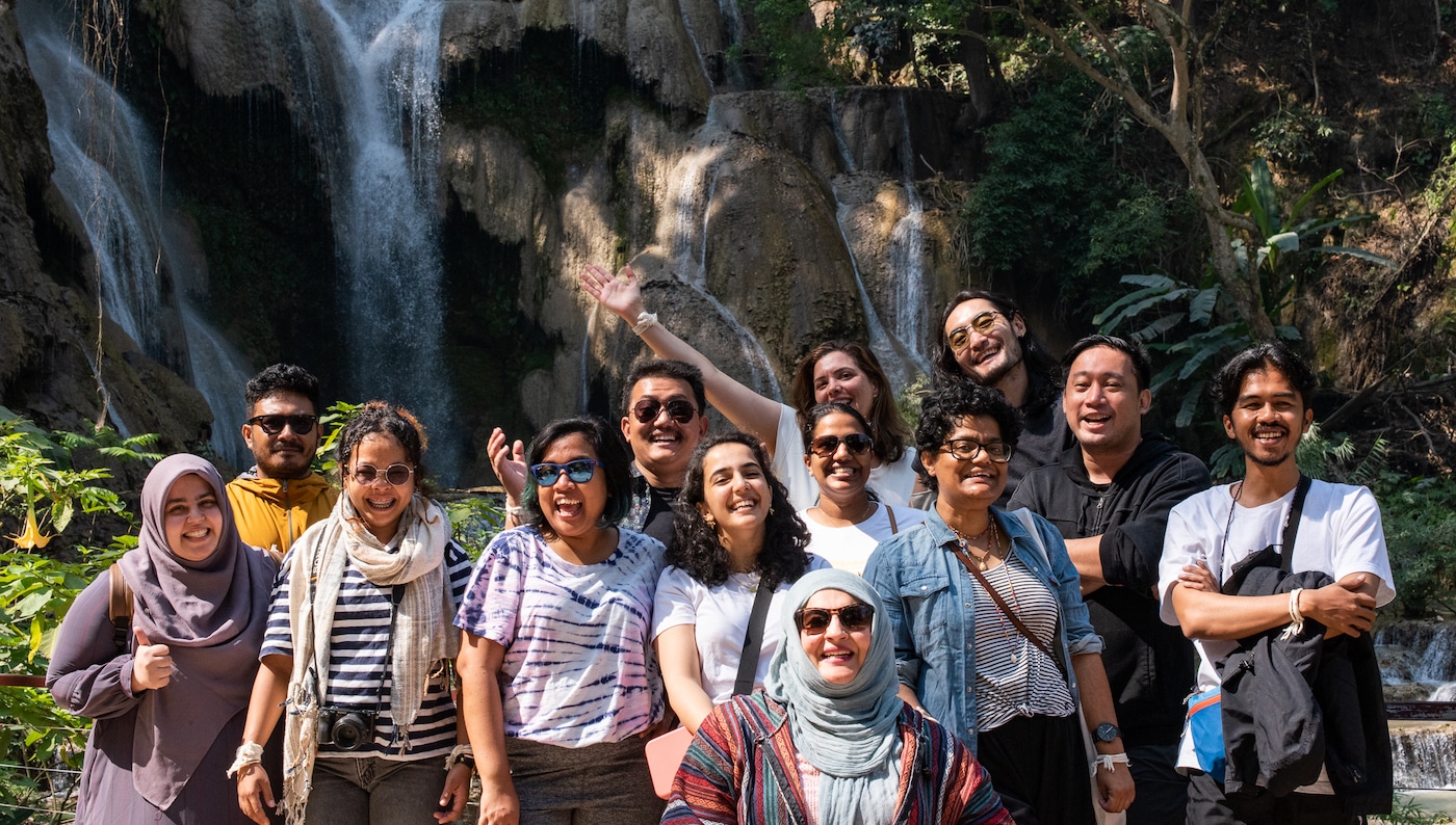 Young Asians stand in front of waterfall