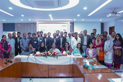 Members of 16 Bangladeshi organizations gather in front of screen with the formal title of the meeting.