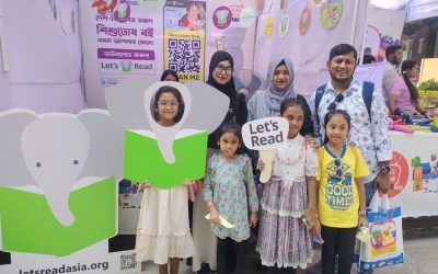 Four Children and their parents stand in front of Let's Read Booth.