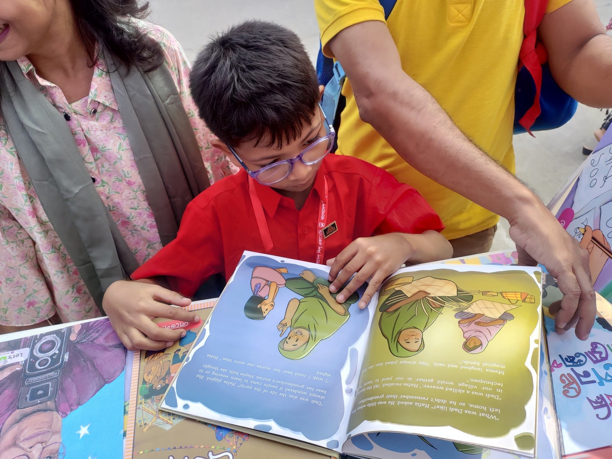A young boy reads a picture book at Let's Read Fair in Bangladesh