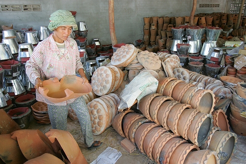 Small- and medium-sized businesses, such as the pottery wholesale shop that Mrs. Kai Savat, picture here, operates are particularly hard-hit by development constraints in Cambodia. Photo By Karl Grobl.