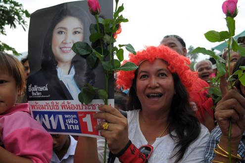 Thai voter holds up Yingluck Shinawatra campaign poster